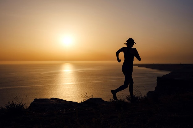 Zijaanzicht van fitnessvrouw die op een weg aan zee loopt