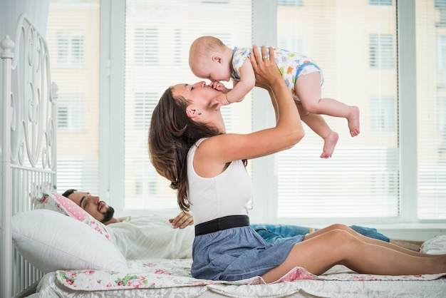 Zijaanzicht van gelukkige jonge ouders die met hun charmante halfjarige baby chatten