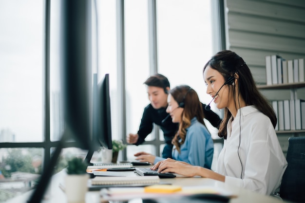 Zijaanzicht van het callcenter van de vrouw met hoofdtelefoons die computers op kantoor gebruiken.