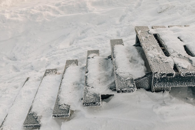 Zijaanzicht van houten loopbrugtrappen bedekt met vorst en sneeuw op een koude winterochtend