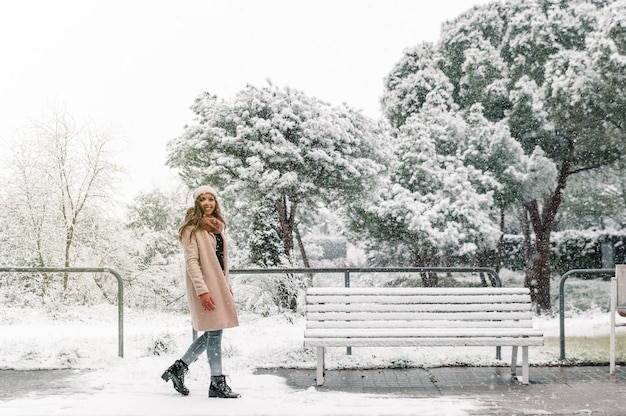 Zijaanzicht van inhoud vrouw in bovenkleding wandelen in besneeuwde park terwijl u geniet van de winter