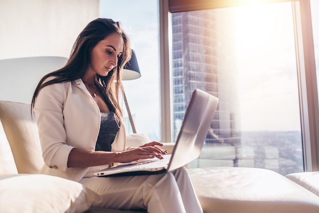 Zijaanzicht van jonge vrouw die op laptop werkt.