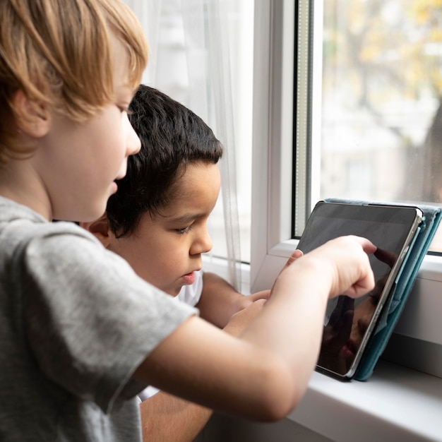 Zijaanzicht van jongens die op tablet thuis spelen