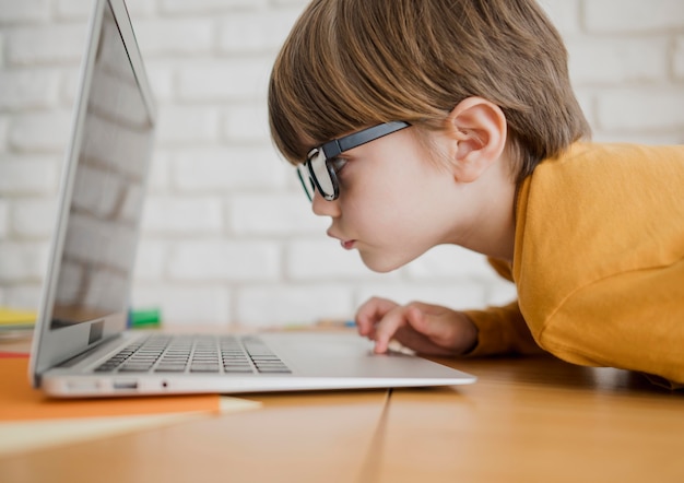 Zijaanzicht van kind met glazen die te dicht worden om laptop te zien