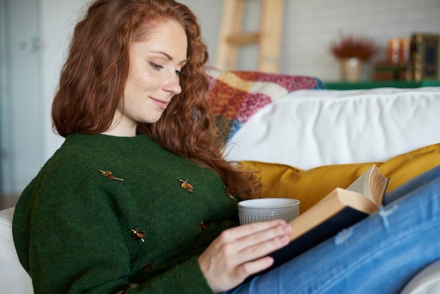 Zijaanzicht van lachende vrouw leesboek in winterdag