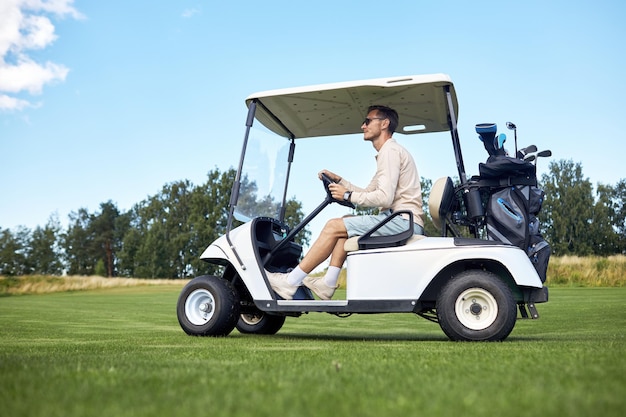 Zijaanzicht van man golfkar rijden over groen veld in sportclub