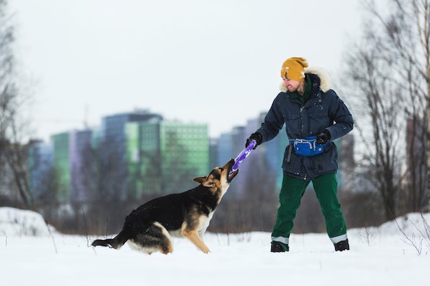 Zijaanzicht van man spelen met herdershond op winterveld