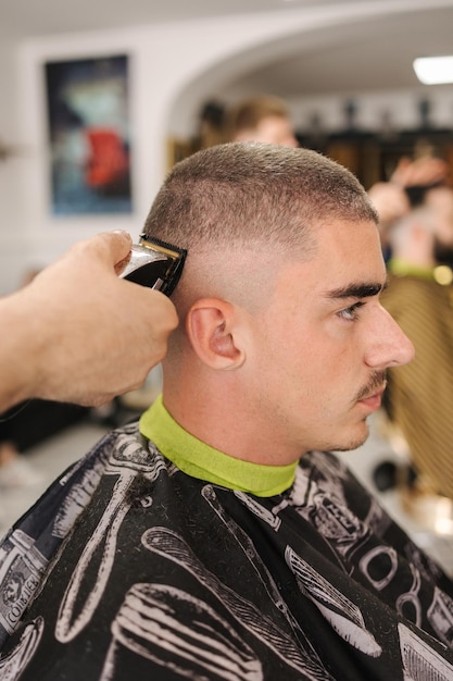 Foto zijaanzicht van mannelijke klant zitten in kapperszaak haar knippen in salon