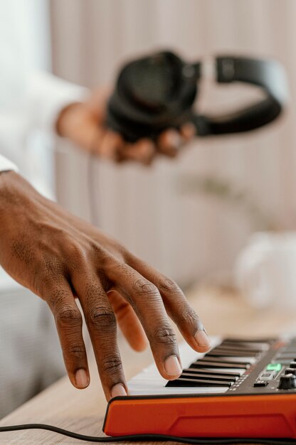 Zijaanzicht van mannelijke musicus die elektrisch toetsenbord speelt en hoofdtelefoons houdt