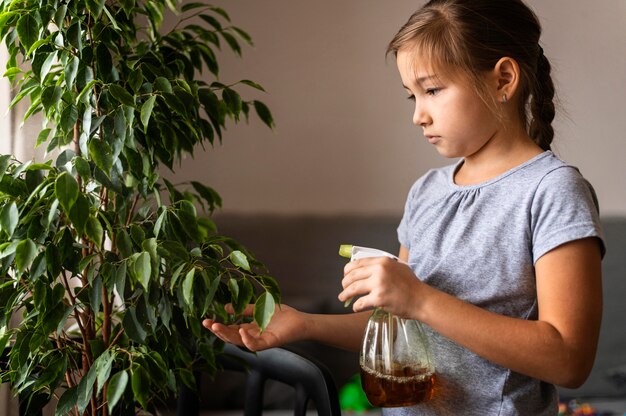 Foto zijaanzicht van meisje sproeiende plant met water