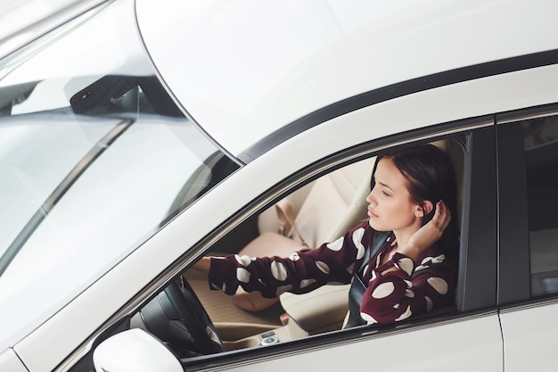 Zijaanzicht van mooie jonge brunette die binnenkant van moderne auto rijden auto