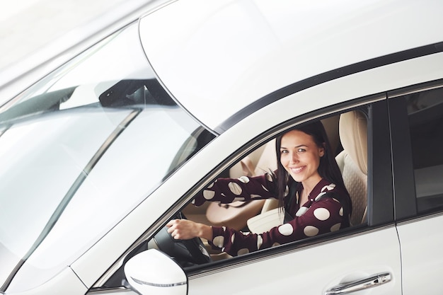 Zijaanzicht van mooie jonge brunette die binnenkant van moderne auto rijden auto