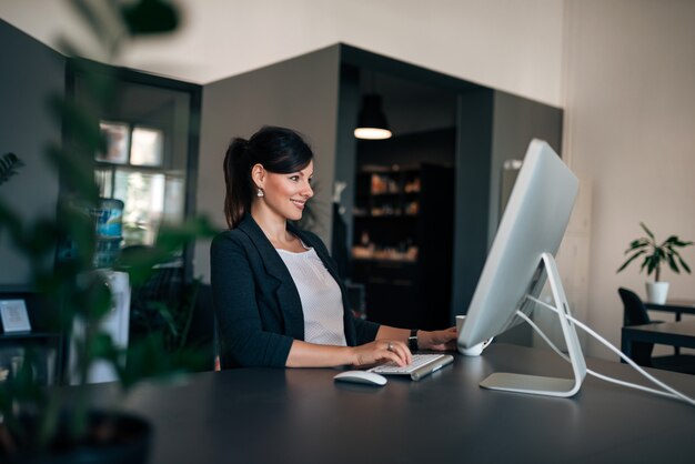 Zijaanzicht van mooie jonge vrouw die aan de computer werkt.