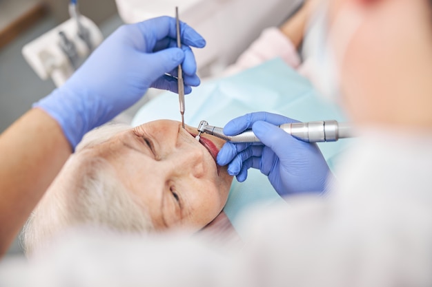 Zijaanzicht van patiënt bij tandheelkundige procedure met behulp van tandheelkundige boor in moderne tandheelkundige kliniek