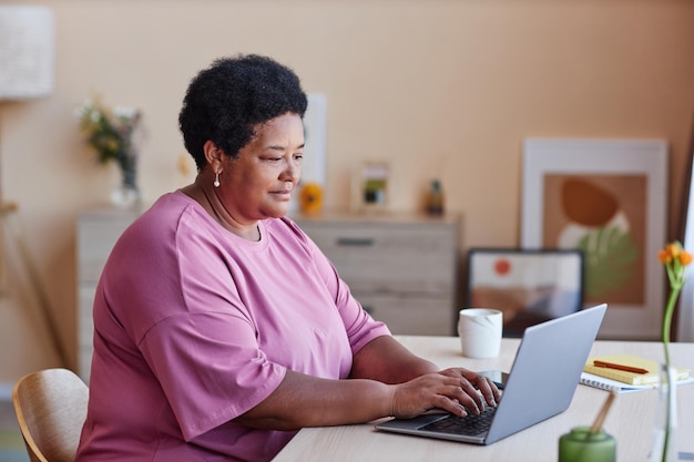 Zijaanzicht van senior Afro-Amerikaanse zakenvrouw typen op laptop toetsenbord