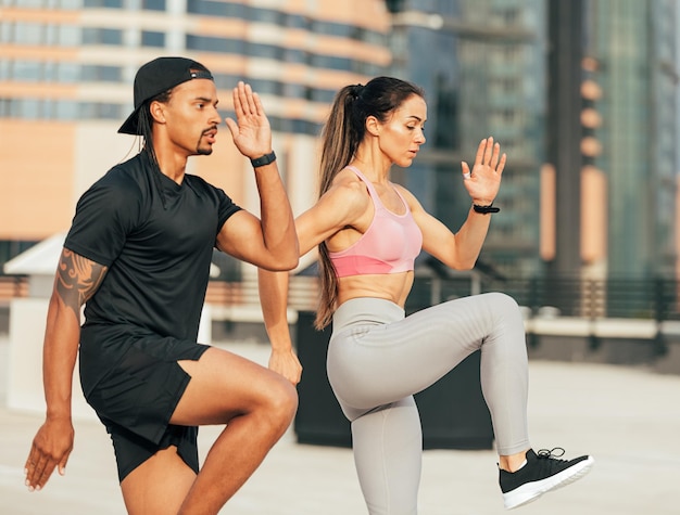 Zijaanzicht van twee mensen in fitnesskleding die samen op het dak springen