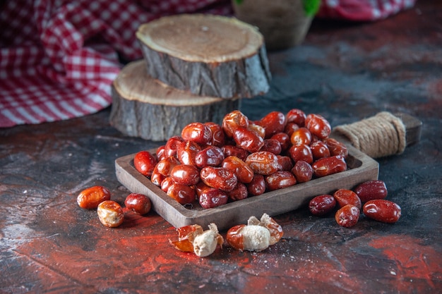 Zijaanzicht van verse rauwe zilverbessenvruchten aan de binnen- en buitenkant van een houten dienblad, bloempot, rode gestripte handdoek op de achtergrond van mixkleuren