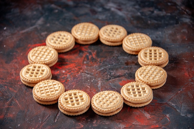 Zijaanzicht van vrije ruimte tussen heerlijke suikerkoekjes gerangschikt in een ronde vorm op mixkleurenachtergrond