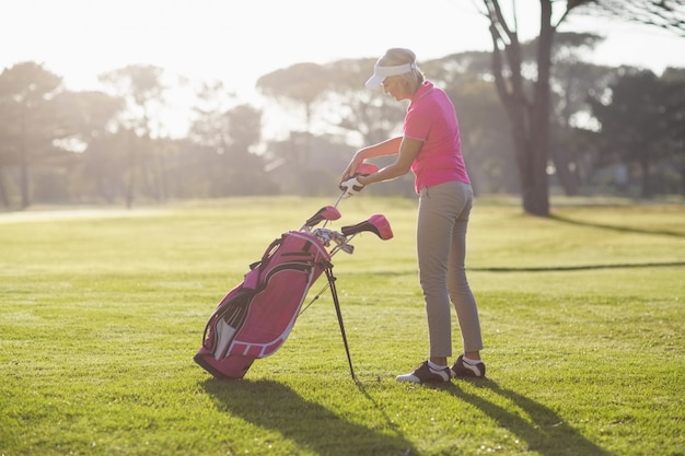 Zijaanzicht van vrouw die golfclub in zak zet