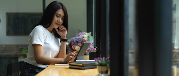 Zijaanzicht van vrouw gericht op digitale tablet in coffeeshop