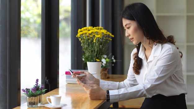 Zijaanzicht van vrouwelijke student met behulp van digitale digitale tablet zittend in café
