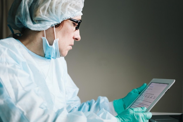 Zijaanzicht van vrouwelijke wetenschapper van middelbare leeftijd die aan tablet in laboratorium werkt