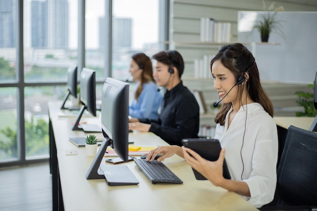 Zijaanzicht van vrouwencallcenter met headsets die computers op kantoor gebruiken