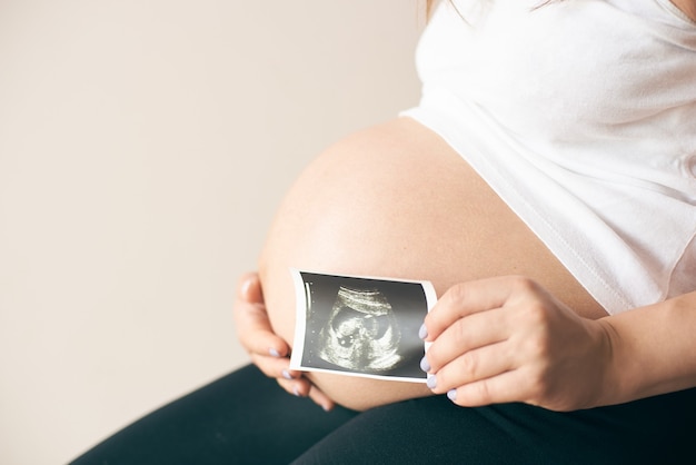 Zijaanzicht van zwangere vrouw met echografie van baby