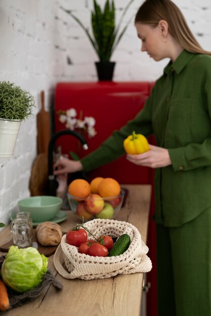 Zijaanzicht vrouw die paprika wast