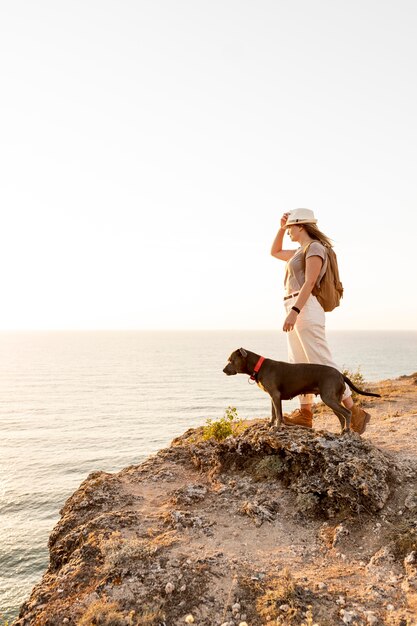 Zijaanzicht vrouw genieten van de zonsondergang met haar hond