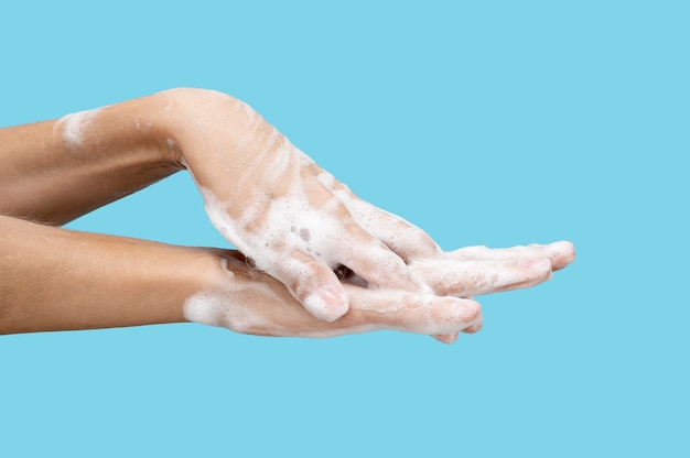 Foto zijaanzicht vrouw haar handen wassen op blauwe achtergrond met kopie ruimte