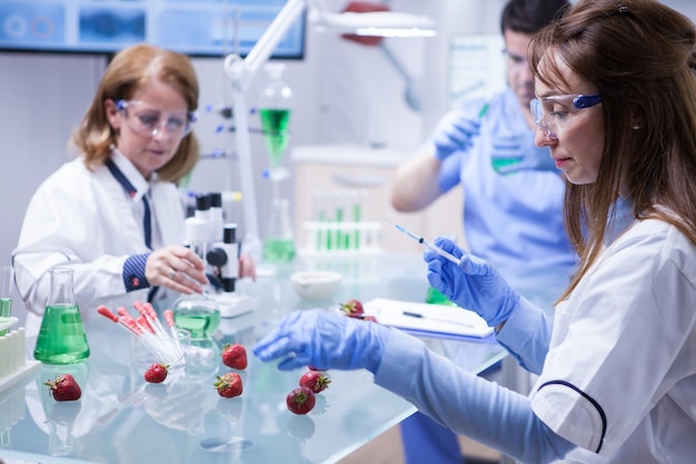 Zijaanzicht vrouwelijke wetenschapper van middelbare leeftijd die test doet op aardbeien in een onderzoekslaboratorium. Gentic test op aardbeien.