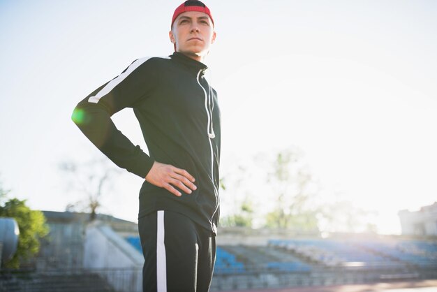 Zijaanzichtbeeld van handosme atletisch mannetje dat wegkijkt en zich voordeed op de baan in het stadion Aantrekkelijke loper die zich voorbereidt op hardlopen en joggen buiten Sportmensen en levensstijlconcept