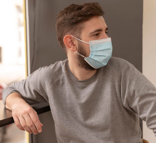 Foto zijaanzichtportret van de jonge mens die een medisch masker draagt