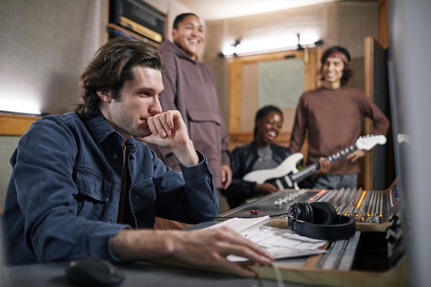 Zijaanzichtportret van muziekband die nieuw album componeert in professionele opnamestudio focus op man