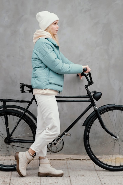 Foto zijaanzichtvrouw die haar fiets houdt