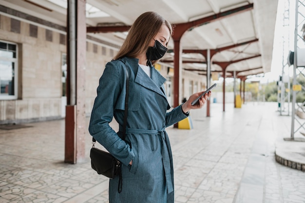 Foto zijaanzichtvrouw die haar mobiele telefoon controleert