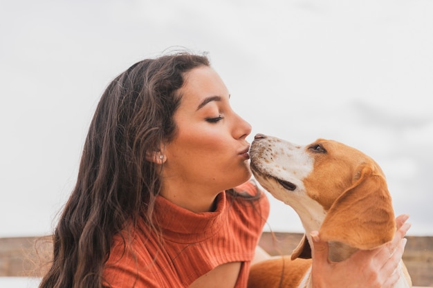 Foto zijaanzichtvrouw die leuke hond kust