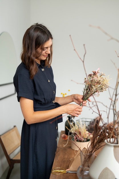 Zijaanzichtvrouw die met droogbloemen werkt