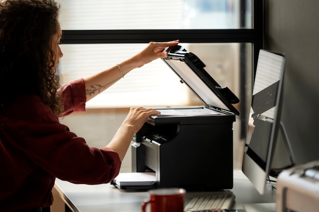 Foto zijaanzichtvrouw die printer gebruikt