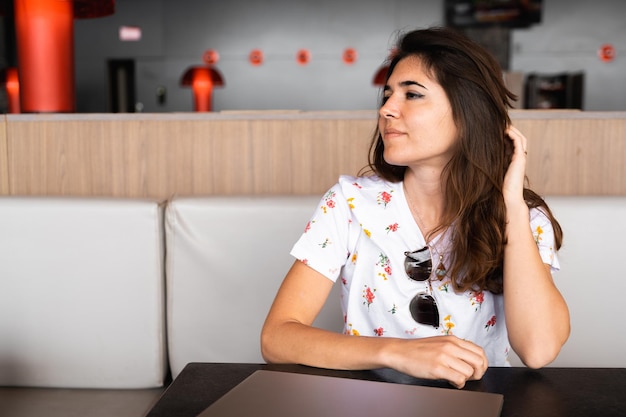 Zijaanzichtvrouw met vrijetijdskleding gesloten ogen die haar haar met handen fixeert Vrouw zit aan tafel