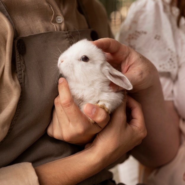 Foto zijaanzichtvrouwen die konijn houden
