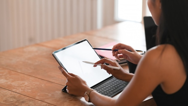 Zijbeeld van mooie vrouw die in gestreept overhemd op de witte lege tablet van de het schermcomputer trekken