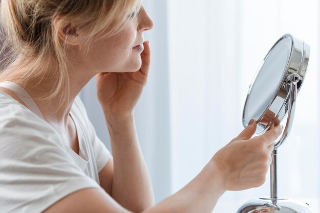 Zijdelings vrouw die in de spiegel kijkt