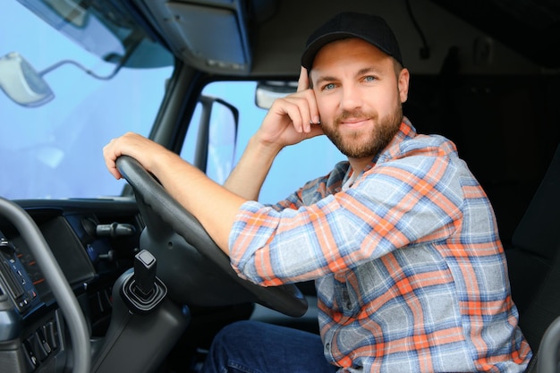 Foto zijkant van de professionele chauffeur achter het stuur in de cabine van de vrachtwagen