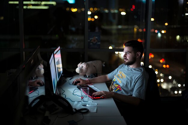 Zijkant van een jonge man die een computer op zijn kantoorbord gebruikt