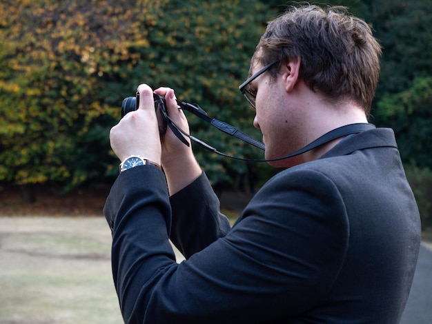 Zijkant van een jonge man die in het park fotografeert