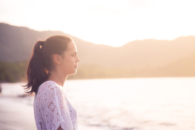 Zijkant van een jonge vrouw die aan de rivier tegen de lucht staat