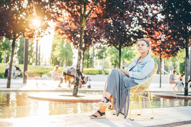 Zijkant van een jonge vrouw die in het park zit