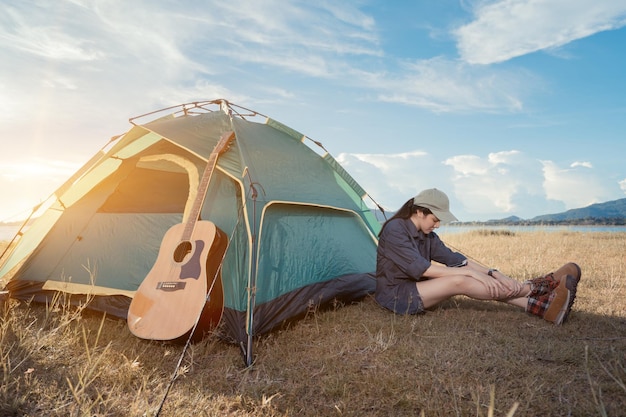 Zijkant van een jonge vrouw die op het land zit bij een tent tegen de lucht